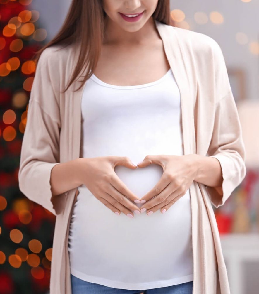 An expectant mother forming a heart over her belly
