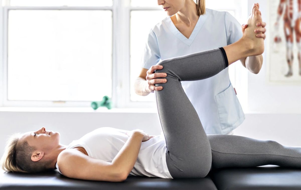 A therapist guiding a client through a leg stretch